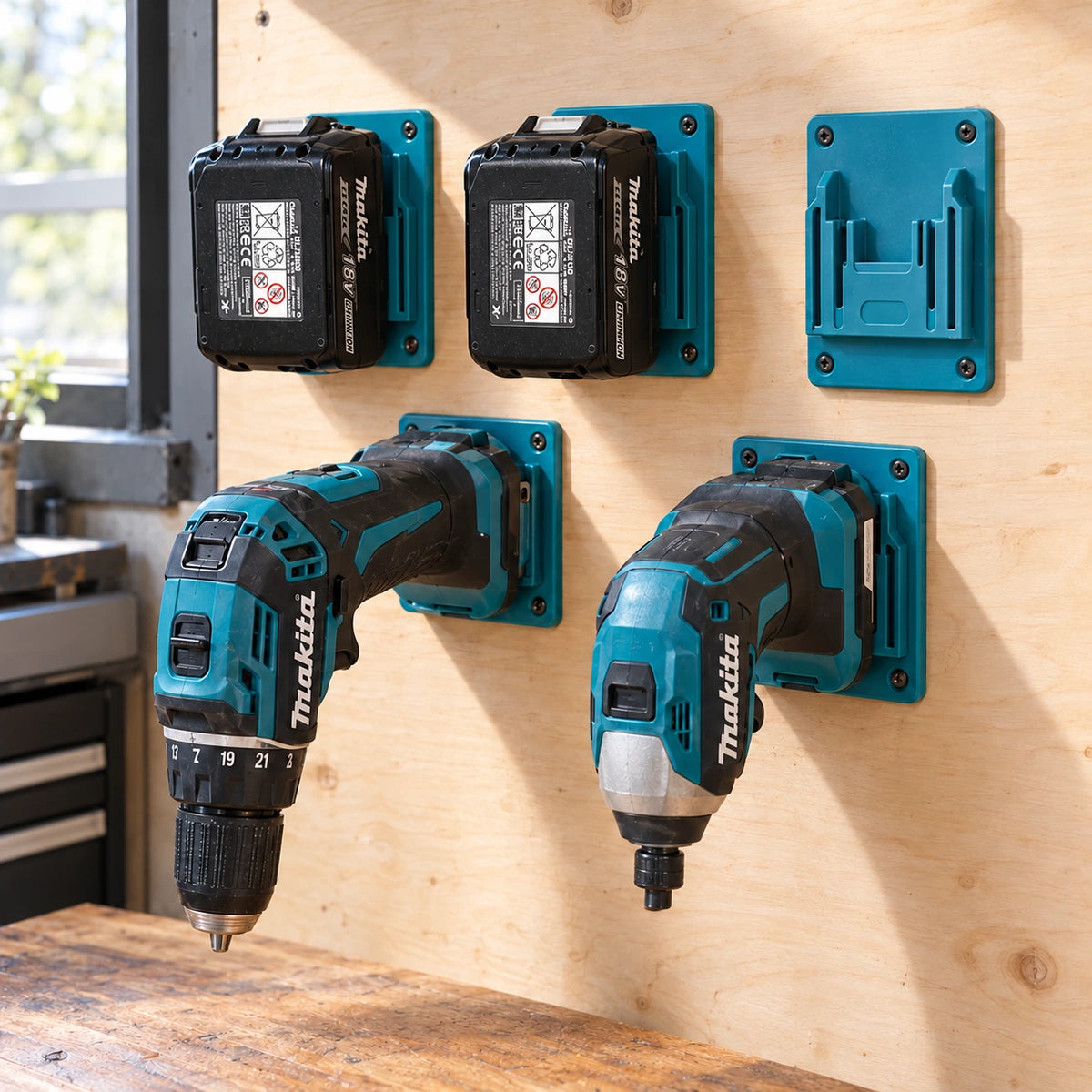 Supporti turchesi su una parete in compensato con due batterie Makita 18V, un trapano avvitatore, un avvitatore a impulsi e un supporto vuoto